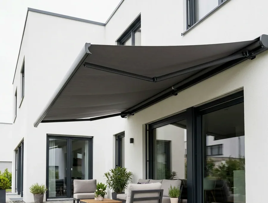 A folding-arm awning extended over a paved patio, fabric canopy carried on two folding arms with no posts in the floor